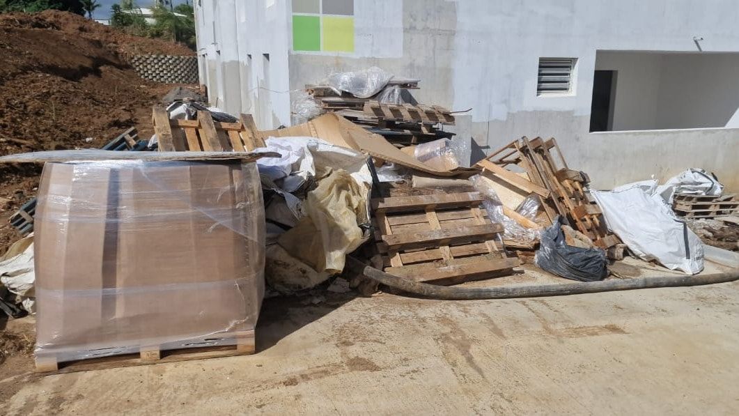 Palettes usagées, cartons, films plastiques et big bags entassés devant un bâtiment neuf