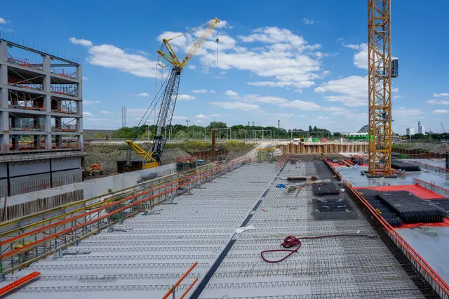 Grue auxiliaire déposant une palette de matériaux sur une dalle
